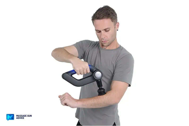 a man holding a massage gun on the right hand while treating the left forearm